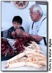 Grandfather and grandson stringing chiles.