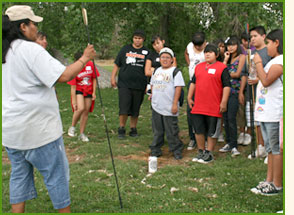 Crow Canyon educator and students, spear-throwing activity.